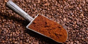 Grinded-coffee-in-vintage-scoop-on-beans.webp